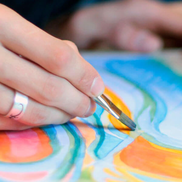 Detailaufnahme einer Frauenhand, die ein Aquarell malt