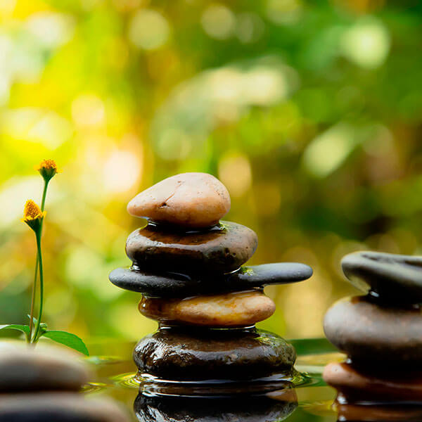 Aufmacherbild von gestapelten, flachen Steinen im Wasser. Das Bild strahlt Ruhe aus.