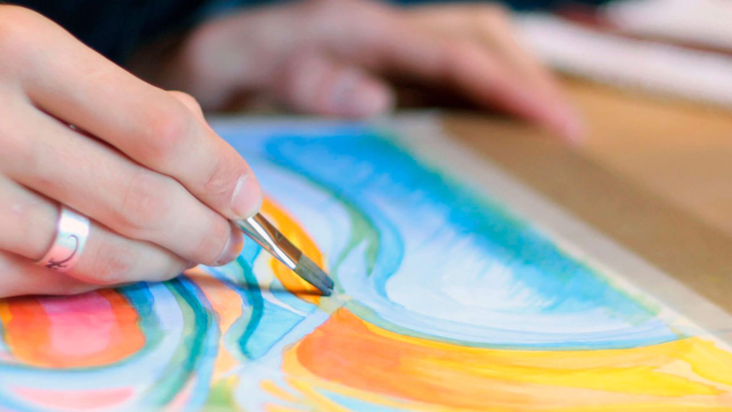 Detailaufnahme einer Frauenhand, die ein Aquarell malt